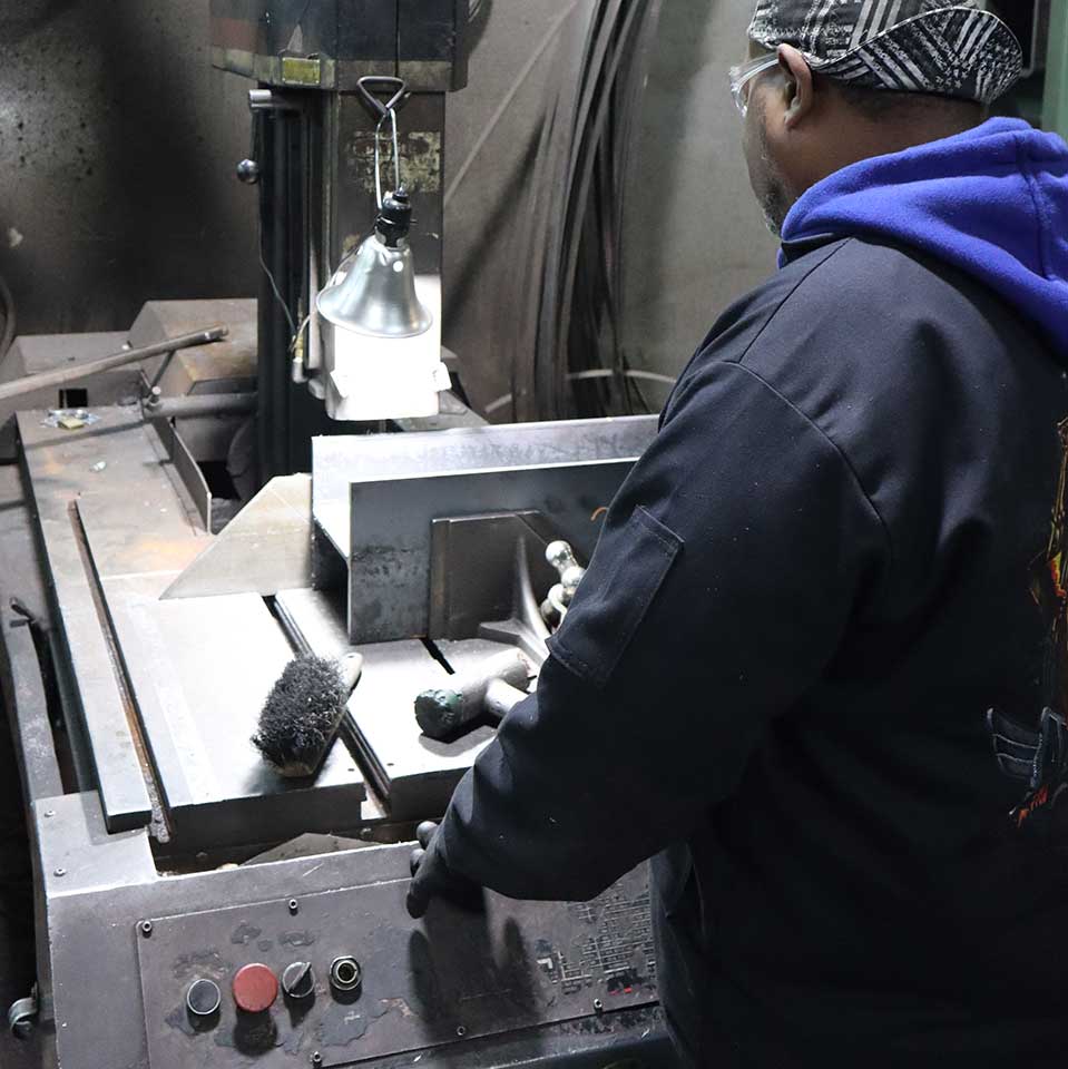 Team member working on metal fabrication equipment at West Point Industries.
