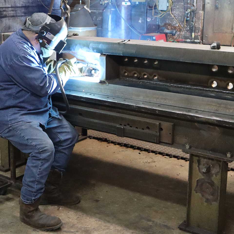 West Point Industries employee welding within the manufacturing facility.